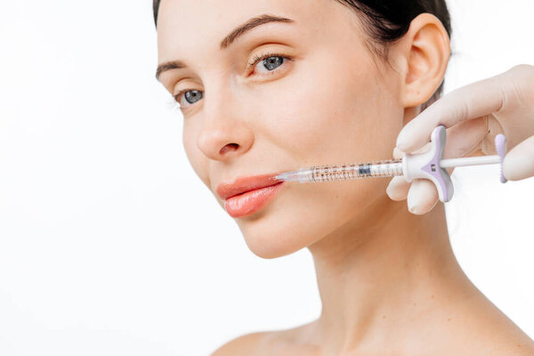 Doctor hand holding a syringe near woman face as she receives a skin lifting injection. This moment emphasizes beauty and modern skincare techniques for a radiant appearance.