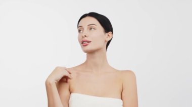 Stüdyoda beyaz arka planda kusursuz tenine hafifçe dokunan güzel genç bir kadın.        