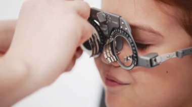 Gözlük takan küçük bir kız göz doktorunun ofisinde görüş kontrolünden geçiyor. Çocukların vizyonlarını tanımlamak ve tedavi etmek için modern yöntemlere bir örnek.