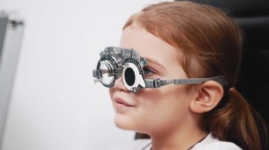 Gözlük takan küçük bir kız göz doktorunun ofisinde görüş kontrolünden geçiyor. Çocukların vizyonlarını tanımlamak ve tedavi etmek için modern yöntemlere bir örnek.