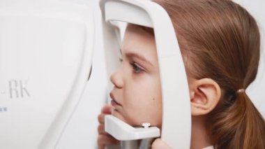 Pediatrik bir göz doktoru küçük bir kızın gözlerini inceliyor. Oftalmik enstrüman. Dikkatli tanı ve çocukların göz sağlığı için bakım.
