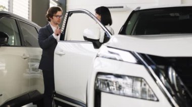 Kendine güvenen araba satıcısı, alıcıyla yeni bir arabanın indirimlerini ve faydalarını tartışıyor.. 