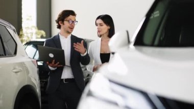 Kendine güvenen araba satıcısı, alıcıyla yeni bir arabanın indirimlerini ve faydalarını tartışıyor.. 