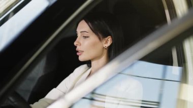 İş kadını arabada güven içinde oturuyor, profesyonellik ve tarz yayıyor. An, dinamik yaşam tarzını ve sürüş özgürlüğünü yansıtan modern hareketliliğin özünü yakalar..