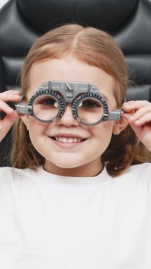 Gözlük takan küçük bir kız göz doktorunun ofisinde görüş kontrolünden geçiyor. Çocukların vizyonlarını tanımlamak ve tedavi etmek için modern yöntemlere bir örnek.