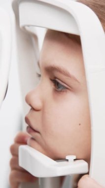 Pediatrik bir göz doktoru küçük bir kızın gözlerini inceliyor. Oftalmik enstrüman. Dikkatli tanı ve çocukların göz sağlığı için bakım.