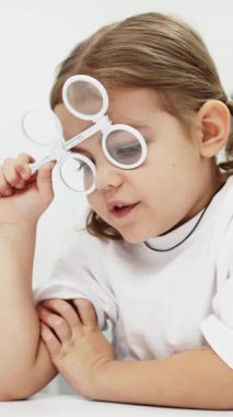 Gözlük takan küçük bir kız göz doktorunun ofisinde görüş kontrolünden geçiyor. Çocukların vizyonlarını tanımlamak ve tedavi etmek için modern yöntemlere bir örnek.