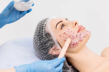 Genç bir kadın lüks bir yüz maskesi tedavisinden zevk alıyor, cildinin parlaklığını arttırıyor. Kaplıcada bir gün, güzellik tedavisi ve rahatlatıcı cilt bakımı..