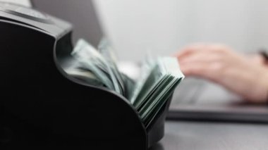 Bir borsacı, dizüstü bilgisayarın önündeki bir hesap makinesinde elinde çizelgeyle dolarları sayar. Dolar, kripto para birimlerini alıp satarak kazanıldı. Finans, bankacılık ve kripto para kavramı.