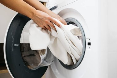 Çamaşır makinesinden giysileri çıkaran kadın elleri.
