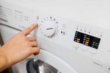 Kadın elinin çamaşır makinesinin düğmelerine dokunuşu.