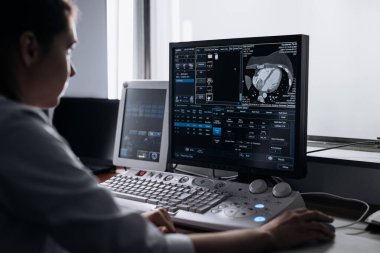 Kadın doktor klinikte bilgisayarın röntgenini inceliyor.