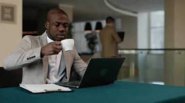 Modern bir iş yerinde çalışan iş adamları. Bir adam iş arkadaşını laptopundaki bir raporla ilgili beyin fırtınasına katılmaya davet eder. Takım çalışması, yaratıcılık ve yenilik kavramı.