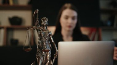 Avukatlık bürosu. Terazili Adalet Anıtı ve dizüstü bilgisayarda çalışan bir avukat. Kavram hukuku, hukuki danışmanlık ve adalet.