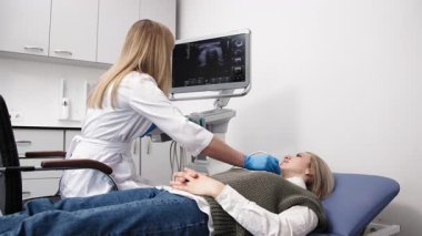 Kadın endokrinolog ultrason ofisinde kadın bir hastaya ultrasonografi yapıyor. Tiroit bezinin ultrason kontrolleri..