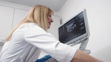 Kadın endokrinolog ultrason ofisinde kadın bir hastaya ultrasonografi yapıyor. Tiroit bezinin ultrason kontrolleri..