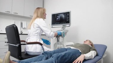 Kadın endokrinolog ultrason ofisinde kadın bir hastaya ultrasonografi yapıyor. Tiroit bezinin ultrason kontrolleri..