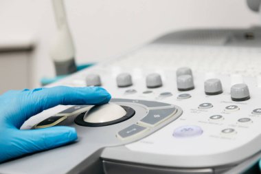 Kadın elleri koruyucu eldivenlerle klinikte ultrasonla çalışıyor.