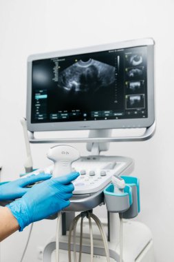 Kadın elleri koruyucu eldivenlerle klinikte ultrasonla çalışıyor.