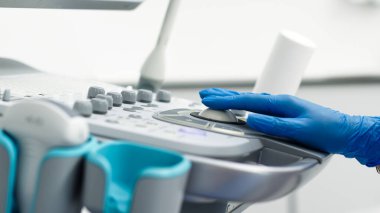 Kadın eli koruyucu eldivende. Klinikte ultrasonla çalışıyor. Görüntüyü kapat.