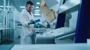 Mavi eldivenli bir bilim adamı, bir şişedeki mavi sıvıyı analiz ediyor ve bir pipetten damlalar ekliyor. Kavram: kimyasal maddeler ve modern araştırma yöntemleri ile hassas bilimsel deneyler.