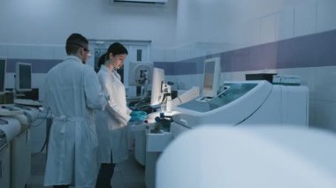 Eldivenli, gözlüklü ve şapkalı bilim adamlarından oluşan bir ekip modern bir laboratuvarda biyokimyasal araştırma yürütüyor. Gelişmiş bilimsel yöntemlerle biyolojik süreçleri öğrenme kavramı.