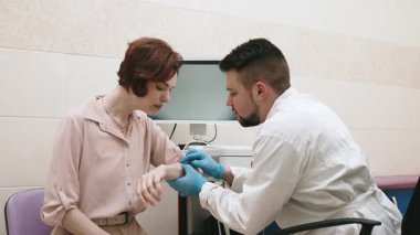 Bir dermatolog modern bir klinikte genç bir hastanın cildini gelişmiş ekipmanlarla inceler ve analiz eder. Deri araştırmaları, onkolojik deri hastalıklarının teşhisi.
