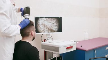 Kafa derisi ve saçın bilgisayarlı incelemesi. Bir tricholog, erkek bir hastanın saç durumunu modern bir merkezde teşhis eder. Gelişmiş tıbbi ve kozmetik hizmetleri kavramı.