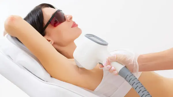 Kadın klinikte lazer tedavisi görüyor, koltuk altındaki kılları alıyor.