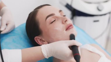 Güzel genç bir kadın klinikte yüz bakımı yaptırıyor.