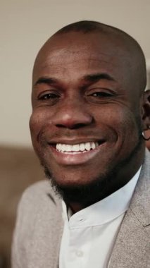 dikey video. Modern ofiste gülümseyen ve kameraya bakan iş adamı Afro-Amerikan erkek. İş hayatında güven, başarı ve profesyonellik kavramı.