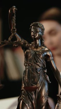 Dikey video. Avukatlık bürosu. Terazili adalet heykeli ve dizüstü bilgisayarda çalışan bir avukat. Hukuk kavramı, hukuki danışmanlık ve adalet.