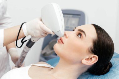 Kadın klinikte lazer tedavisi görüyor, saç prosedürünü kaldırıyor.