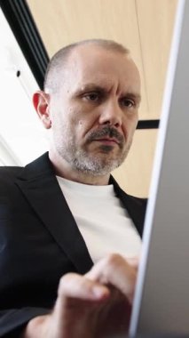 Dikey video. Elinde dizüstü bilgisayarı olan bir iş adamının fotoğrafı olumlu haberler alıyor. Başarılı bir anlaşma ve başarılı bir iş anlayışı..