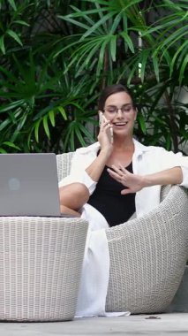 Bilgisayarla çalışırken telefonla konuşan modern bir iş kadını. Modern bir ofiste profesyonel bir yönetici iş görüşmesi yapıyor. İş kavramı, çoklu görev ve verimli iş akışı.