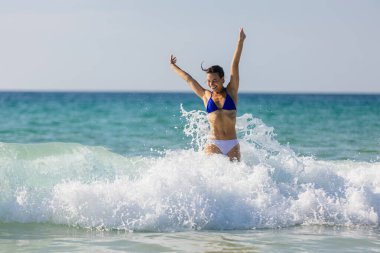 Genç bir kadın okyanustaki dalgaların arasında dinlenmekten zevk alıyor. Seyahat, rahatlama ve eğlence kavramı.
