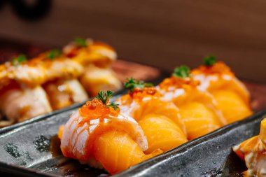 Suşi siyah bir tabakta yuvarlanıyor. Somonlu suşi. Suşi. Suşi ruloları. Suşi. Suşi ruloları. Japon mutfağı. Japon restoranı..
