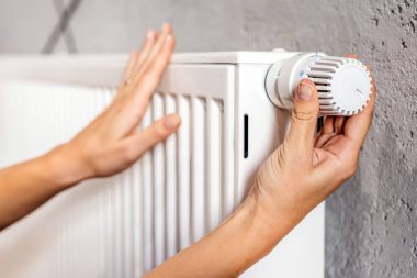  Radyatörün sıcaklığını ayarlayan bir el. Enerji tasarrufu, ısıtma sistemleri ve ev konforunu vurgulayan bir kavram. Enerji tasarruflu yaşam ve kışlık ev çözümleri için ideal.