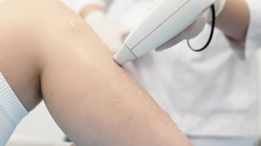 Genç bir kadın modern bir güzellik salonunda bacaklarında lazer tüyü temizleme tedavisi görüyor. Son derece etkili teknoloji kavramı ve şık bir kaplıca ortamında müşteri rahatlığı.