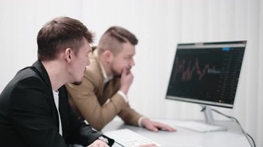 : İki tüccar bir bilgisayarda kripto para çizelgelerini tartışıyor, finansal riskleri analiz ediyor ve yatırım kârlarını tahmin ediyor. Konsept piyasa araştırmaları, yatırımlar ve bilgilendirilmiş kararlar.