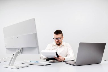 Ofisteki bilgisayarda çalışan bir işadamı, borsa ve enflasyon çizelgelerini analiz ediyor, kağıtları düzenliyor. Konsept, ekonomik durgunluk zamanlarında gergin karar verme sürecini yakalamak.