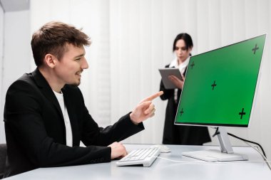 Modern bir ofiste Chroma Key yeşil ekranlı bir masaüstü bilgisayarı üzerinde çalışan bir bilişim uzmanı. Dijital yenilikleri, çevrimiçi iş stratejilerini ve veriye dayalı karar verme mekanizmasını kavrayın.