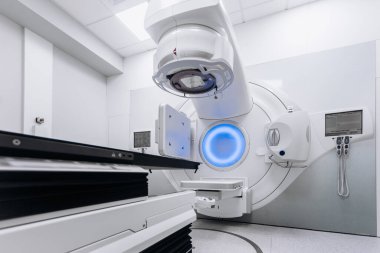 Hasta radyoterapi için doğrusal hızlandırıcı üzerinde yatarken, tıbbi uzman ekipmanları kontrol cihazı kullanarak çalıştırıyor. Gelişmiş makine ve modern klinik ayarları kesin tedaviyi sağlar