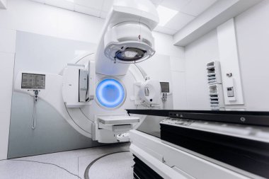 Hasta radyoterapi için doğrusal hızlandırıcı üzerinde yatarken, tıbbi uzman ekipmanları kontrol cihazı kullanarak çalıştırıyor. Gelişmiş makine ve modern klinik ayarları kesin tedaviyi sağlar