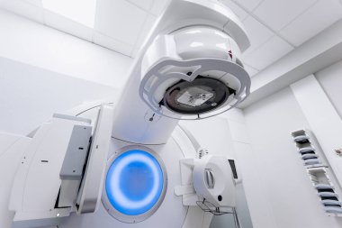 Hasta radyoterapi için doğrusal hızlandırıcı üzerinde yatarken, tıbbi uzman ekipmanları kontrol cihazı kullanarak çalıştırıyor. Gelişmiş makine ve modern klinik ayarları kesin tedaviyi sağlar