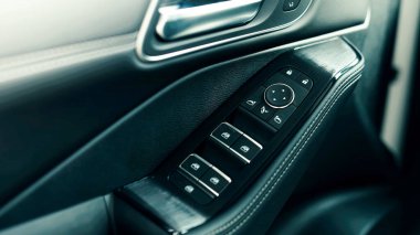 Araçlarda kullanılan modern tasarım ve yüksek kaliteli materyalleri vurgulayan, pencere ve kilit düğmeleri olan bir araba kapısı kontrol panelinin ayrıntılı yakın plan görüntüsü