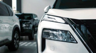 Çağdaş bir sergi salonunda sergilenen gösterişli beyaz araç, modaya uygun tasarımını ve yenilikçi özelliklerini ön plana çıkarıyor.