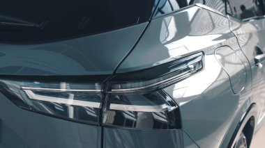 Modern araba arka penceresi parlak yansımaları ve ambiyansı olan çağdaş bir sergi ortamında şık arka lambaları ve şık tasarım özelliklerini ön plana çıkarıyor