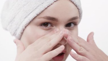 Kadın yüz temizleme rutininden sonra burnuna dokunuyor.