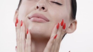 Kadın yüzüne nazikçe kırmızı tırnaklarla dokunuyor.